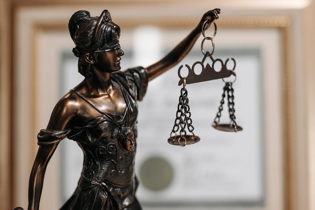 creative Close-up of a bronze Lady Justice statue holding scales in an office environment.